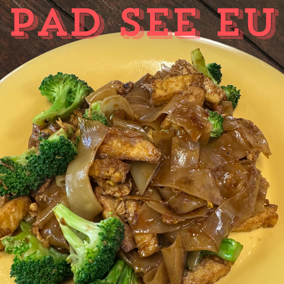 Pad See Ew with wide noodles, tofu, and broccoli on a yellow plate from Tasty Thai Campus.